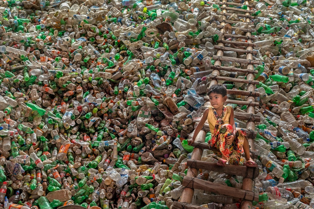 Το αγοράκι κάθεται σε μια σκάλα σε εργοστάσιο ανακύκλωσης πλαστικών μπουκαλιών στο Μπαγκλαντές. Η ανακύκλωση έχει αρχίσει να γίνεται μια αναπτυσσόμενη βιομηχανία στη χώρα, η οποία όμως εξακολουθεί να βασίζεται στα ανθρώπινα χέρια για τη συλλογή και διαλογή αντικειμένων προς ανακύκλωση