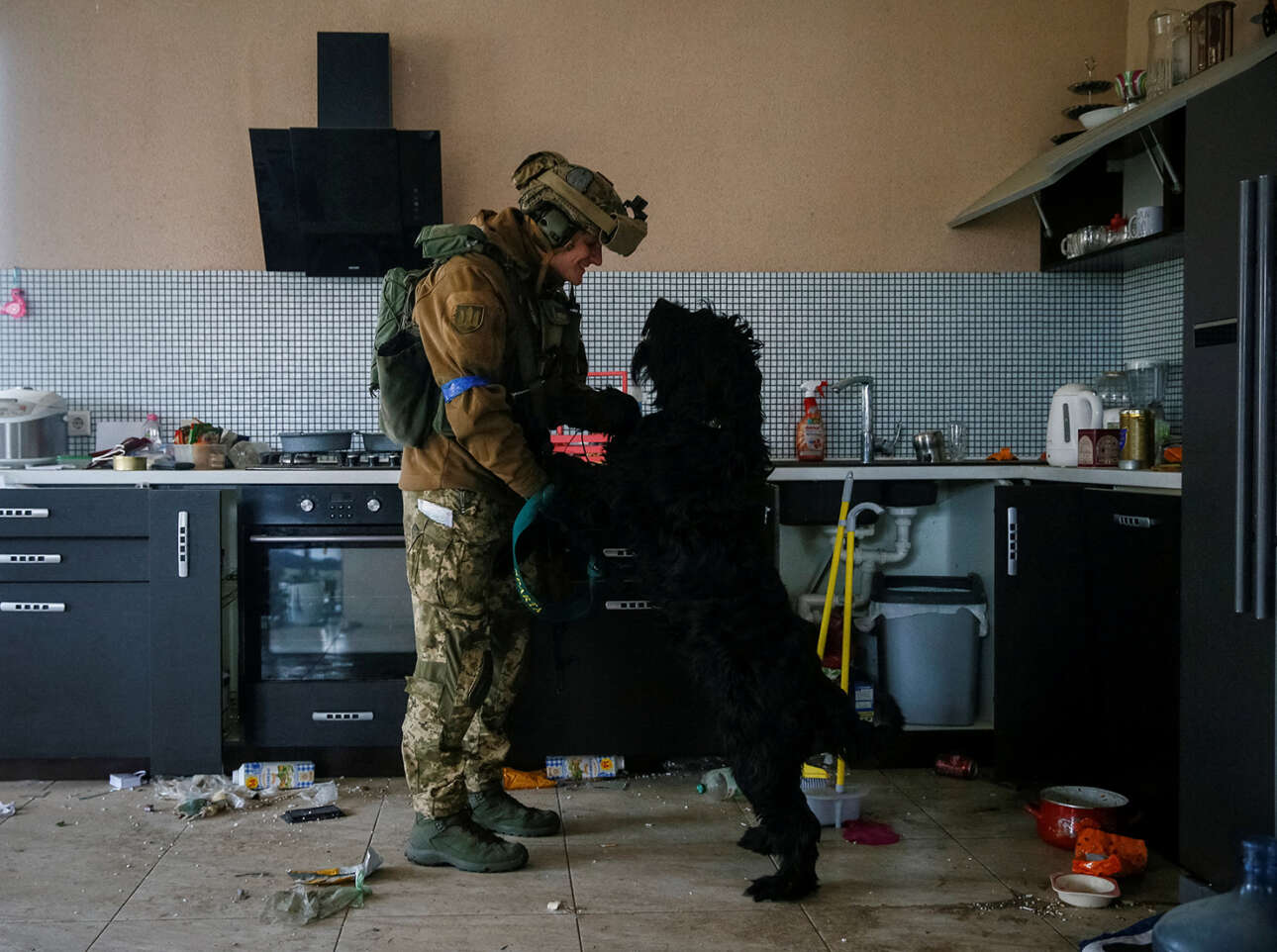 Ουκρανός στρατιώτης αγκαλιάζει τον σκύλο που άφησαν πίσω οι ιδιοκτήτες του στο σπίτι που εγκατέλειψαν, κοντά στην πρώτη γραμμή του Κιέβου