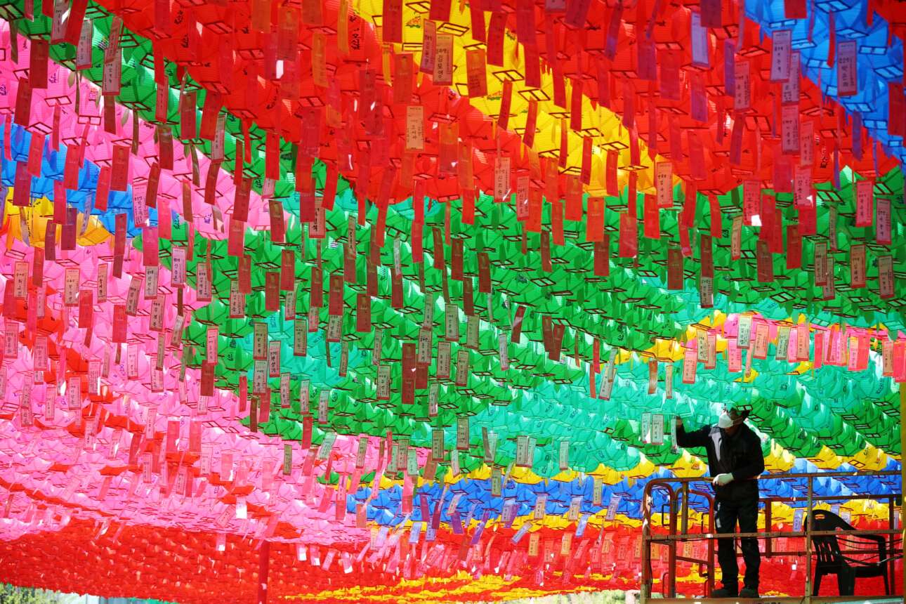 Ακόμη ένα καρέ με θρησκευτικό υπόβαθρο, από βουδιστικό ναό της Σεούλ αυτή τη φορά: ο εργάτης κρεμάει στα πολύχρωμα φαναράκια τα χαρτάκια των πιστών με τις ταπεινές τους παρακλήσεις για καλή υγεία, κ.λπ. – όλα αυτά στο πλαίσιο της προετοιμασίας για τον επερχόμενο εορτασμό των γενεθλίων του Βούδα 